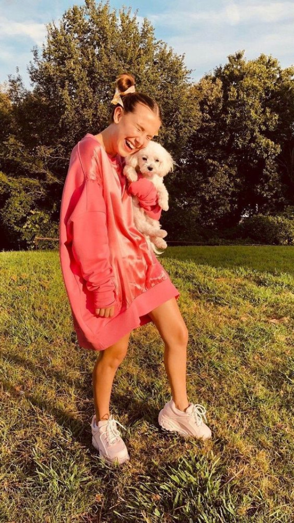 Stepping Out in a Lively Coral Dress and Casual Sneakers, She's Geared up for a Park Day with Her Delightful Canine Pal