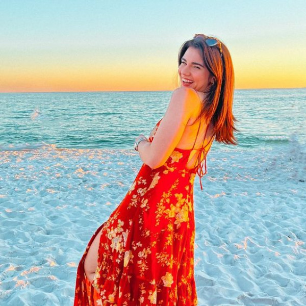 Brett Cooper's beautiful red dress twirls on the sandy shore, she's like a dream!